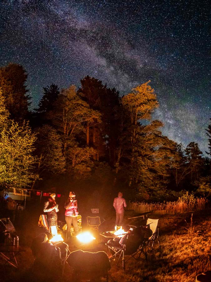 Campers sitting under the Milky Way around Snow Peak Takibi fire pits powered by Zutto SP1 propane gas adapters creating smokeless flames