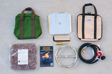 Overhead view of the complete Zutto SP1 smokeless propane gas adapter kit showing burner, tray, air mixer, regulator hose, lava rocks, canvas bags, protector sleeve, and user manual