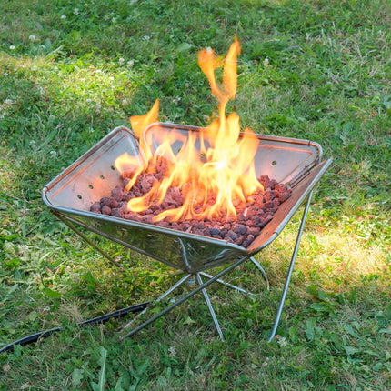 Angled view of the Zutto SP1 smokeless propane gas adapter burning inside a Snow Peak Takibi L fire pit placed on grass