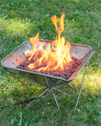 Angled view of the Zutto SP1 smokeless propane gas adapter burning inside a Snow Peak Takibi L fire pit placed on grass
