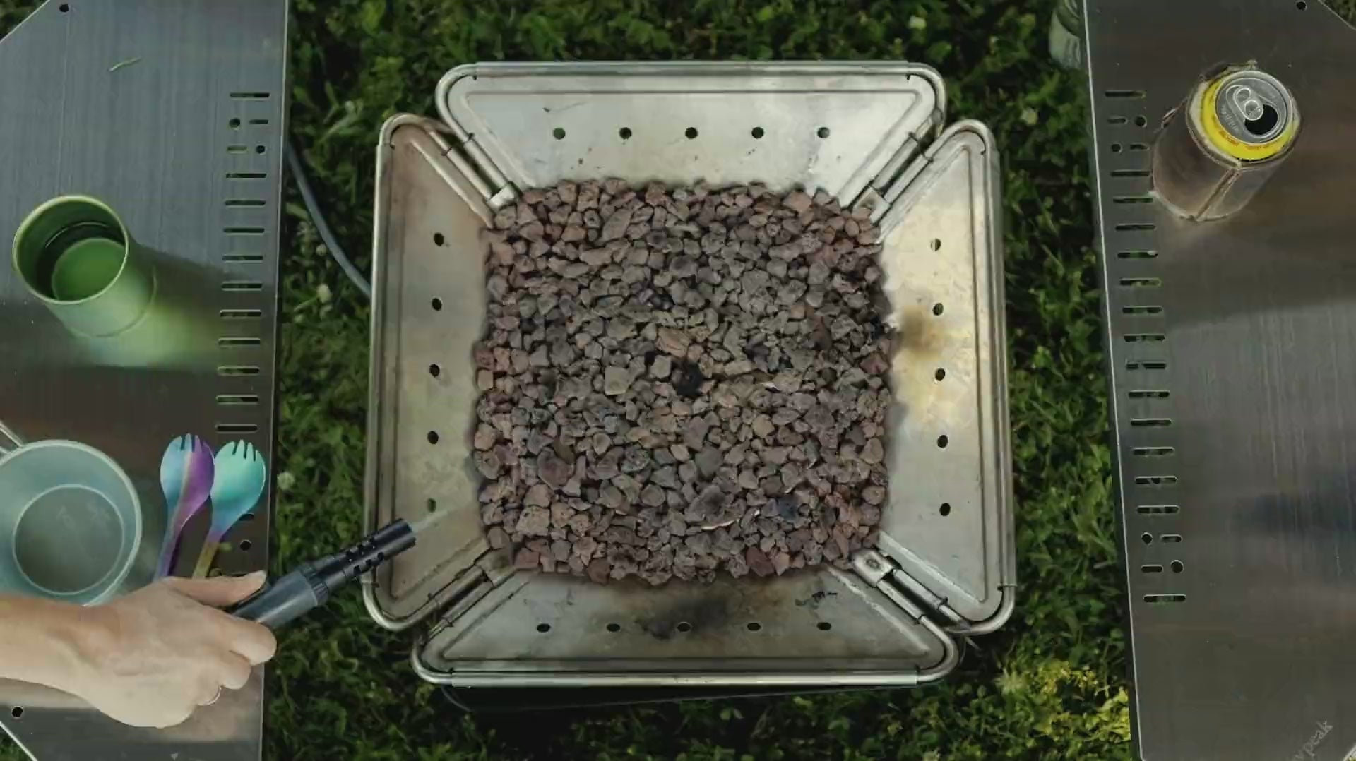 Overhead looping video of the Zutto SP1 smokeless propane gas adapter being lit inside a Snow Peak Takibi fire pit surrounded by a Jikaro table with utensils and a drink, showing a unique top-down view of a campfire setup with text overlays saying:
Your favorite fire pit deserves an upgrade
No tools, no mods, no smoke
Instant and reversible